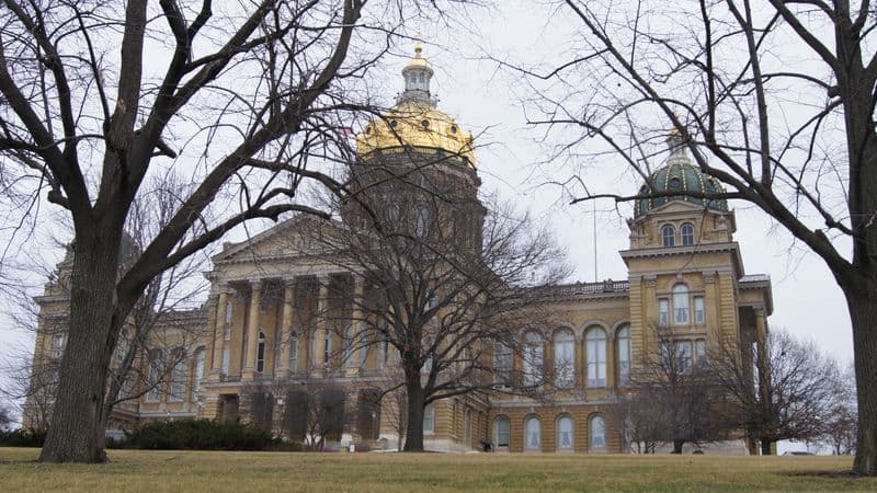The Iowa State Capitol in Des Moines, with its gold dome, seen through bare winter trees